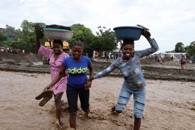 Women hold belongings as they cross a flooded area after heavy rains brought by Hurricane Melissa caused deadly flooding, in Petit Goave, Haiti October 31, 2025.