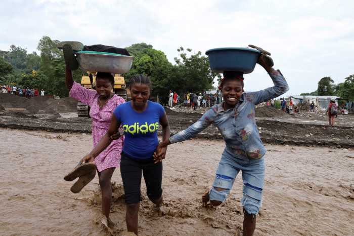 Women hold belongings as they cross a flooded area after heavy rains brought by Hurricane Melissa caused deadly flooding, in Petit Goave, Haiti October 31, 2025.