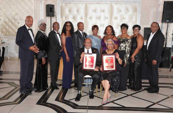 Sitting in front with plaques, journalist and humanitarian Michael Wattkis and Dr. Montrae Calhoun Thomas, a pediatrician in New Jersey who were honored at the Caribbean Medical Mission (CMM) Black Tie gala in NJ. Looking on are some of the board members of the CMM.