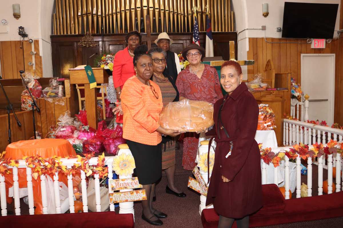 The Decorations Committee members display a large bread to be cut up and distributed to congregants.