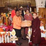 The Decorations Committee members display a large bread to be cut up and distributed to congregants.
