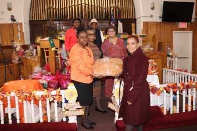 The Decorations Committee members display a large bread to be cut up and distributed to congregants.