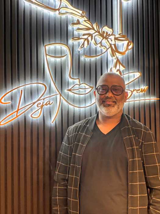 Déjà Brew Café owner Suraj Sooroojballie, a Guyanese-born entrepreneur, stands inside his Queens location, which blends Caribbean warmth with Manhattan sophistication.