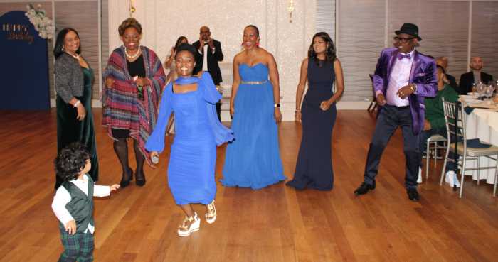 A little worshiper, foreground joins churchgoers dancing to Gospel hit “Very Big God” to celebrate the pastor's 60th birthday, and the renewing of his 35th wedding vows in the ballroom of the elegant Crescent Beach Club in Bayville Long Island, on Nov. 7. Lead vocalist, Christine Anato, front, and pastor Joe's sister, Susan Persaud fourth from left.