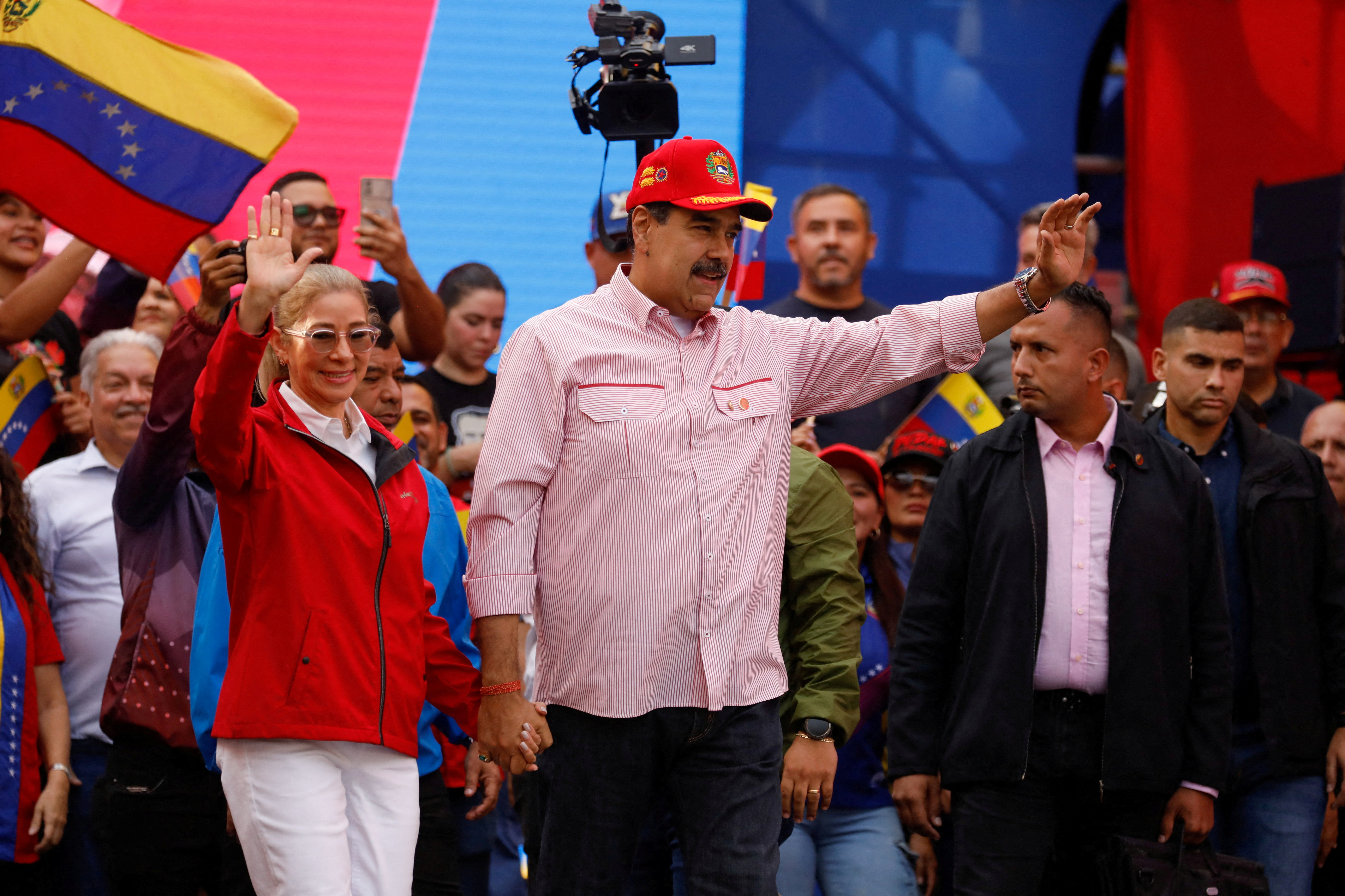 Venezuela's President Nicolas Maduro waves while holding the hand of his wife Cilia Flores during a ceremony to swear in new community-based organizations, as U.S. President Donald Trump’s administration ramps up pressure on Maduro’s government, in Caracas, Venezuela, December 1, 2025.