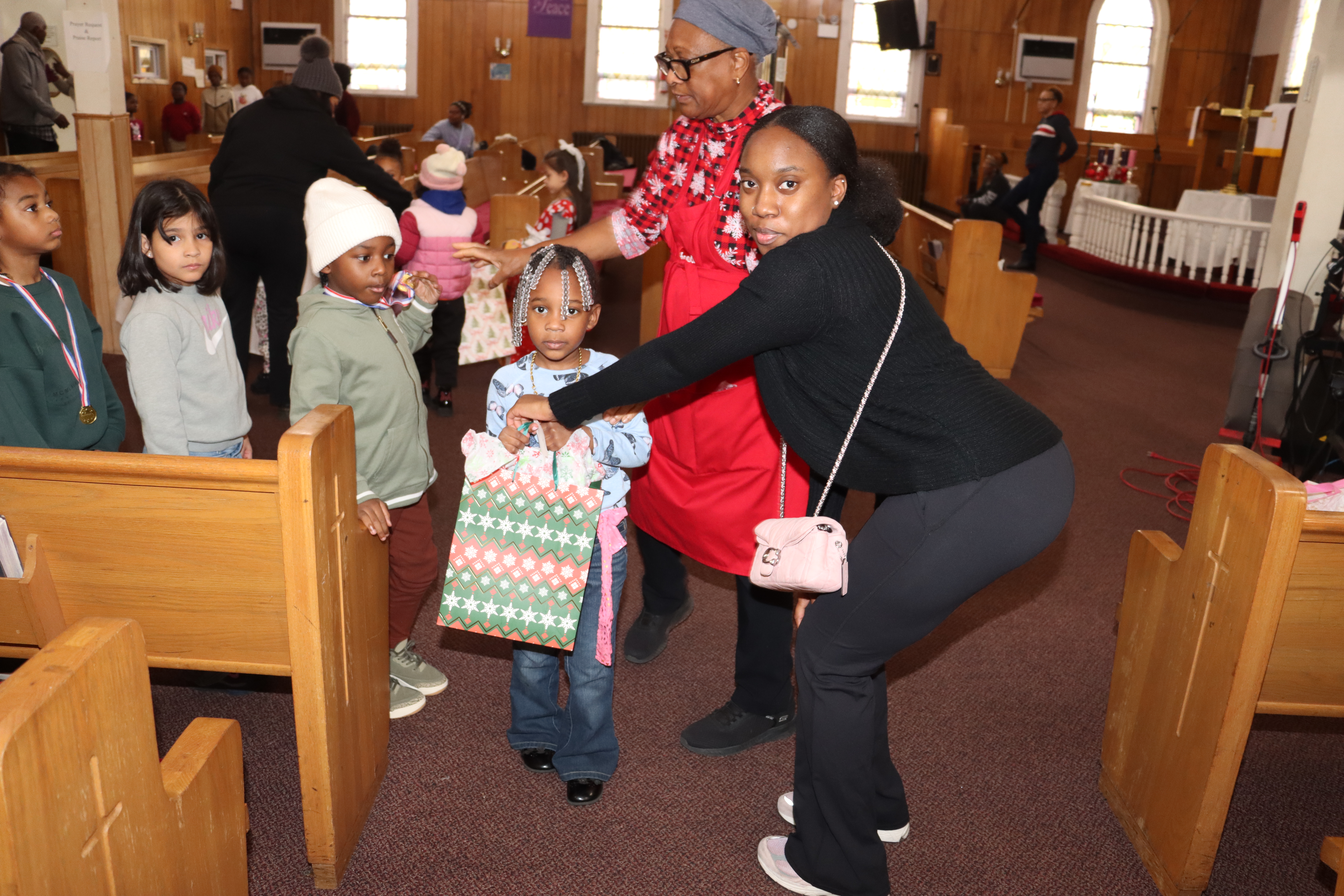 A volunteer, foreground, right, assists Sis. Joycelyn King, in distributing Christmas gifts to children.
