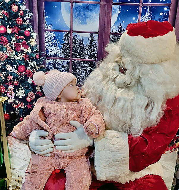 A child looks at Santa Claus with wonder, having seen him for the first time.