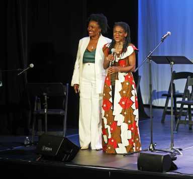 Curators Heather Simms and Patrice Johnson Chevannes standing next to each other on stage at the Billie Holiday Theater for the celebration on Dec. 13, 2025.