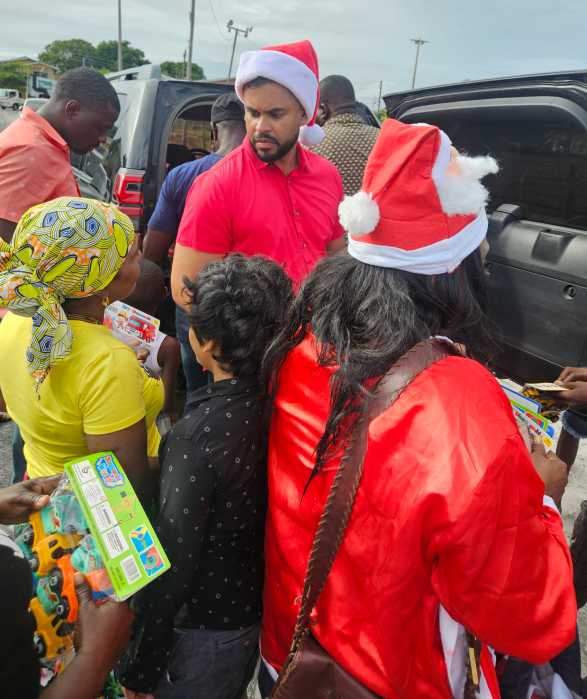 Guyana’s Minister of Culture, Youth and Sports, Charles S. Ramson, center, surrounded by boys and girl waiting to be presented with toys, at a Dec. 21 distribution in Agricola Village, on the East Bank of Demerara.