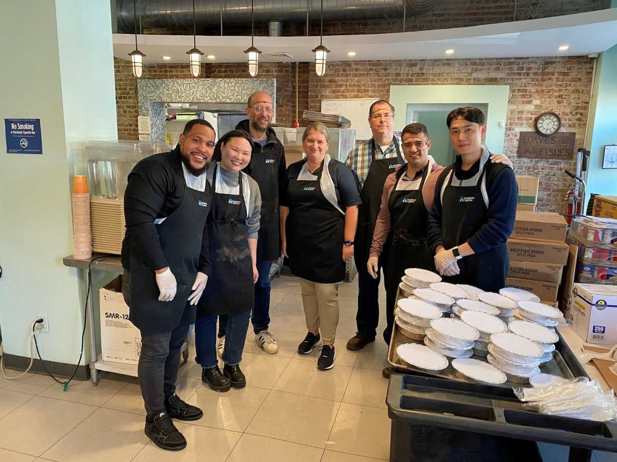A group of volunteers standing in a room at the Brooklyn-based organization Neighbors Together, which is a soup kitchen, social service hub, and community advocacy center.