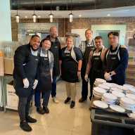 A group of volunteers standing in a room at the Brooklyn-based organization Neighbors Together, which is a soup kitchen, social service hub, and community advocacy center.