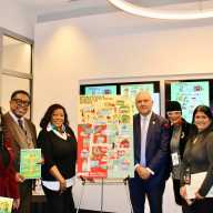 Proud Guyanese stand next to one of 23 Illustrations of the Mayor's Office of Immigrant Affairs exhibition, showcasing a poster with Guyana Gateway in Brooklyn, and Little Guyana in Queens and the Bronx. The launch of the pop-up exhibition was held on Dec. 10 at 253 Broadway in NYC. From left, Claire Patterson-Monah, Dr. Terrence Blackman, Brooklyn Community Board 17 Manager, Sherif Barker, Commissioner Manuel Castro, Caribbean Life's contributor Tangerine Clarke, Sookranie Dhanpat, and Pastor James Richmond.