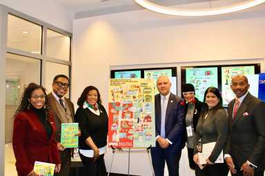 Proud Guyanese stand next to one of 23 Illustrations of the Mayor's Office of Immigrant Affairs exhibition, showcasing a poster with Guyana Gateway in Brooklyn, and Little Guyana in Queens and the Bronx. The launch of the pop-up exhibition was held on Dec. 10 at 253 Broadway in NYC. From left, Claire Patterson-Monah, Dr. Terrence Blackman, Brooklyn Community Board 17 Manager, Sherif Barker, Commissioner Manuel Castro, Caribbean Life's contributor Tangerine Clarke, Sookranie Dhanpat, and Pastor James Richmond.