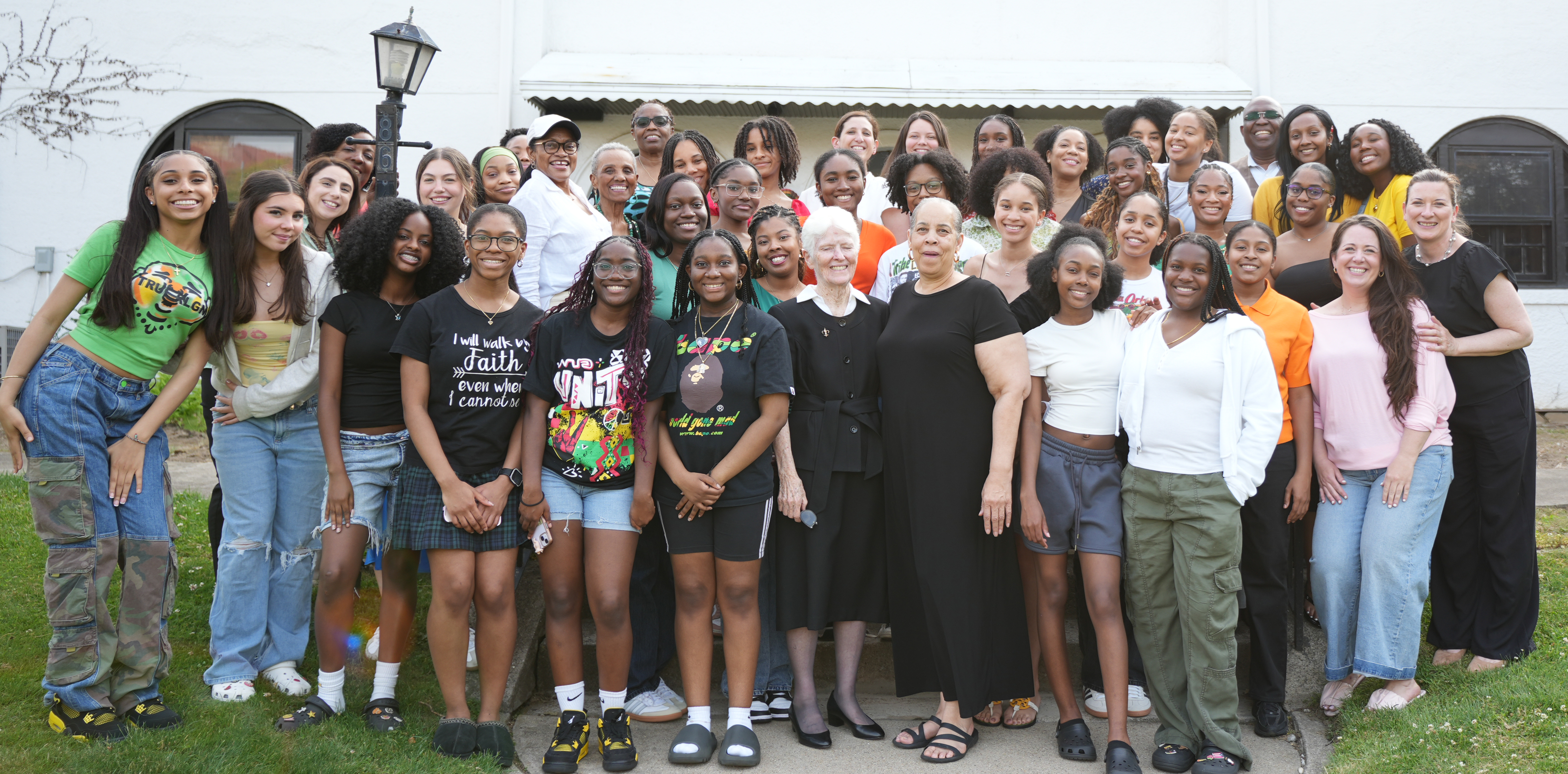 Current members and alumni of the BSU/AHCCC, along with faculty, staff, and the Sisters of Saint Joseph (CSJ), gather in front of the original convent — once home to the CSJ educators who led TMLA for decades — during the May 2025 TMLA Black Student Union / African Heritage and Caribbean Culture Club five-year anniversary celebration.