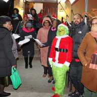 Grenadian Nataly Wilson, foreground, plays "The Grinch" during community caroling on the steps of Fenimore Street United Methodist Church on Christmas Eve.