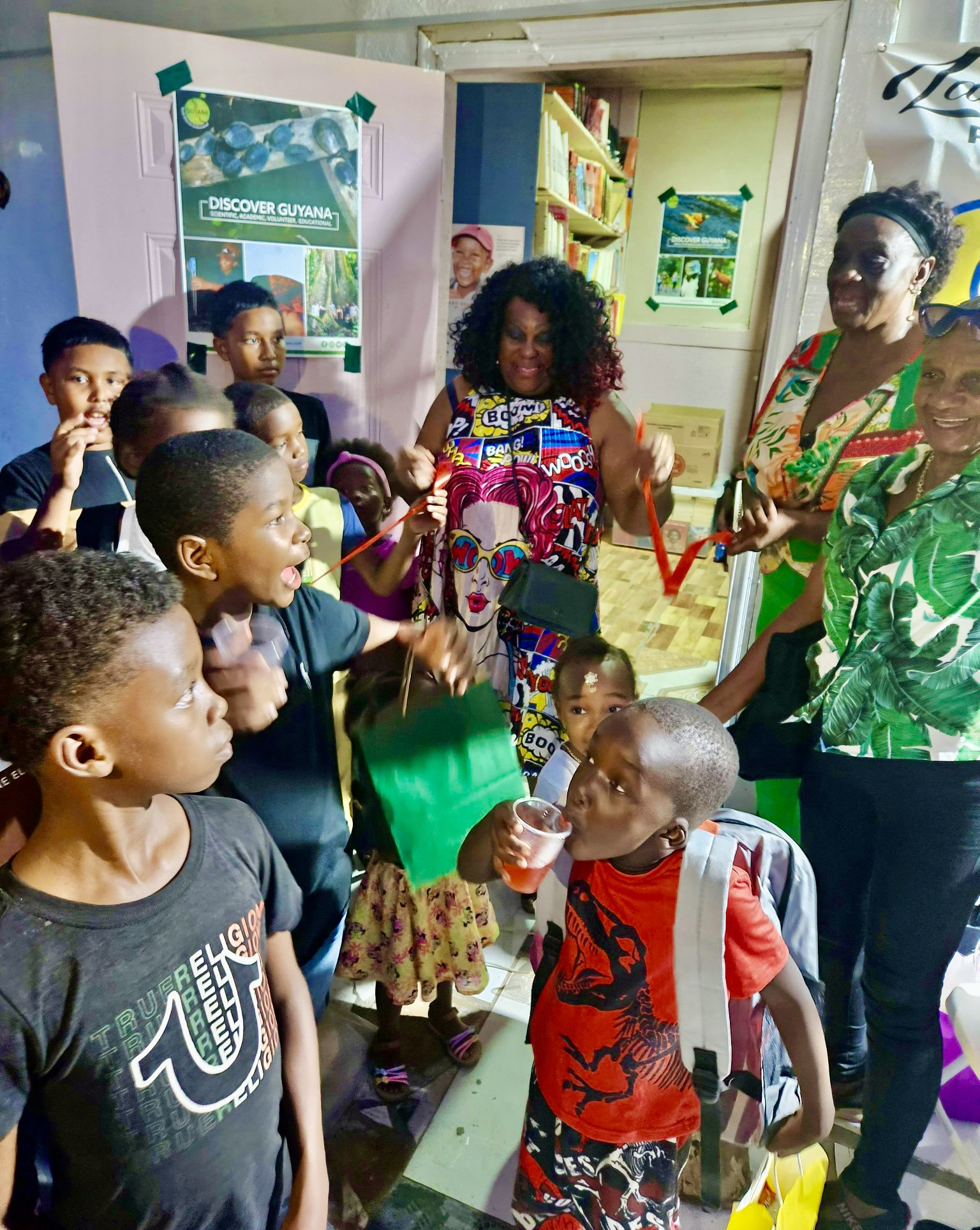 President of the New Jersey-based Guyana Heritage Foundation Inc, Lady Ira Lewis flashes a big smile, as the happy kids looks on during a ribbon-cutting ceremony to unveil the Lady Ira Family Empowerment (LIFE) Library in the small Agricola Village, on the East Bank of Demerara in Guyana. The very first public reading room was launched on Jan. 10, 2026.