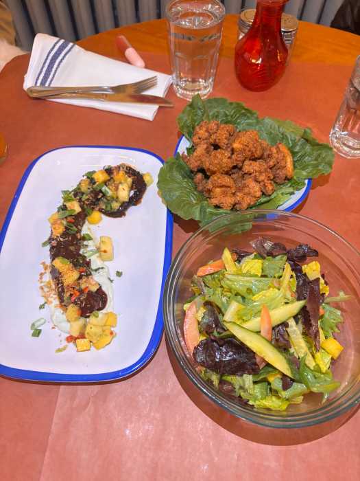 A table is set with Bar Manje dishes, including jerk octopus, a mixed salad and chicken bites, showcasing Chef Kingsley John’s modern approach to Caribbean-inspired small plates and entrees.