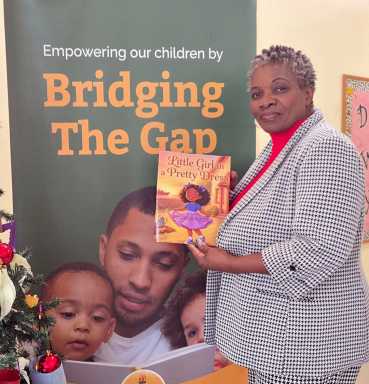 Caren Charles De Freitas holding her first children's book, "Girl in a Pretty Dress."