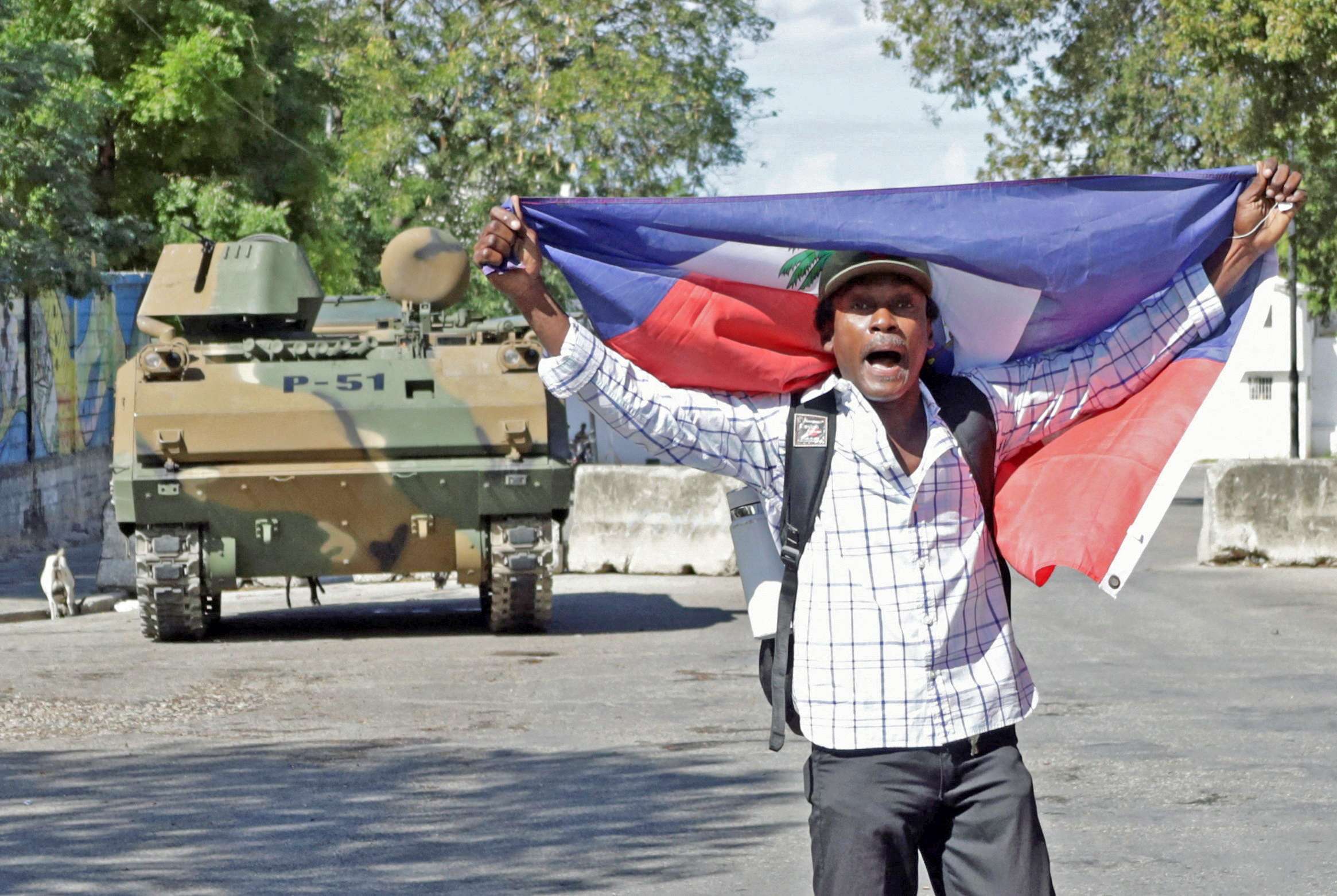 A man protests holding a Haitian flag while Haitian security forces guard the Prime Minister's office and the headquarters of the Transitional Presidential Council (CPT), as the mandate of the transitional governing council, formed to curb gang violence and pave the way for long-delayed election, is set to end on February 7 with no succession plan in place, in Port-au-Prince, Haiti, Feb. 6, 2026.