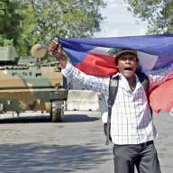 A man protests holding a Haitian flag while Haitian security forces guard the Prime Minister's office and the headquarters of the Transitional Presidential Council (CPT), as the mandate of the transitional governing council, formed to curb gang violence and pave the way for long-delayed election, is set to end on February 7 with no succession plan in place, in Port-au-Prince, Haiti, Feb. 6, 2026.