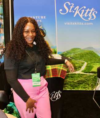 Chimarie Morillo St. Kitts & Nevis Tourism Authority Midwestern Sales Representative in the United States, poses for a picture against the backdrop of pristine landscapes of St. Kitts during the recent 2026 New York Travel & Adventure Show at the Jacob Javits Center.
