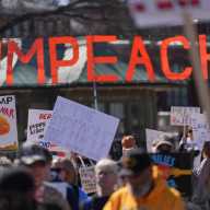 Demonstrators hold signs during the March4Democracy rally and march in Washington D.C., U.S., February 28, 2026.
