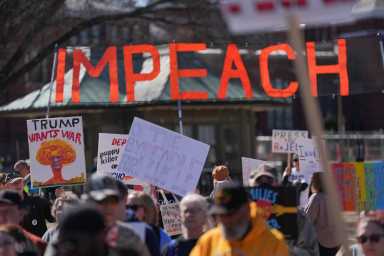 Demonstrators hold signs during the March4Democracy rally and march in Washington D.C., U.S., February 28, 2026.