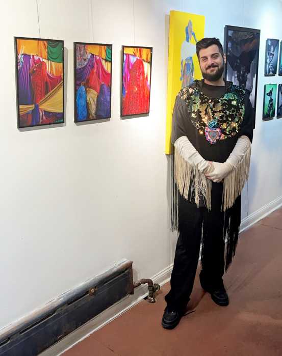 Steven Baboun stands in front of his vibrant, color-inspired exhibition, reflecting the playful use of color during carnival celebrations.