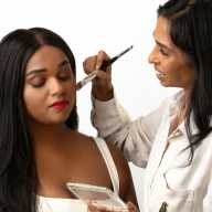Priya Permaul Thomas applies makeup to a client during a demonstration, emphasizing the brand’s focus on mature skin and precise color matching.