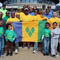 Walkathon participants, with Consul General Roland "Patel" Matthews, holding SVG national flag, second from left, in front of the pavilion at Marine Park in Brooklyn.