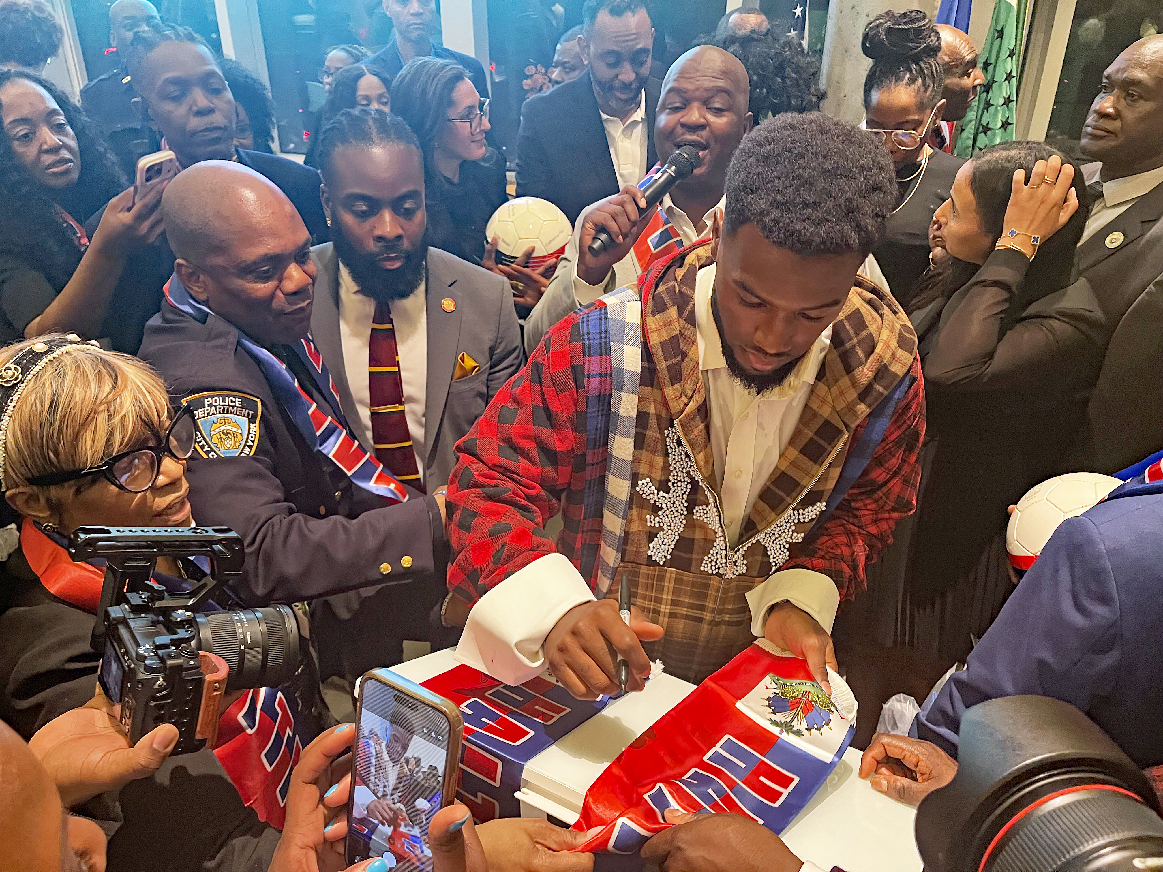 Duckens Nazon signs a Haitian flag at the Museum of Contemporary African Diasporan Arts (MoCADA) Gallery + Café in Brooklyn during “A Night for Haiti” event on April 13, 2026.