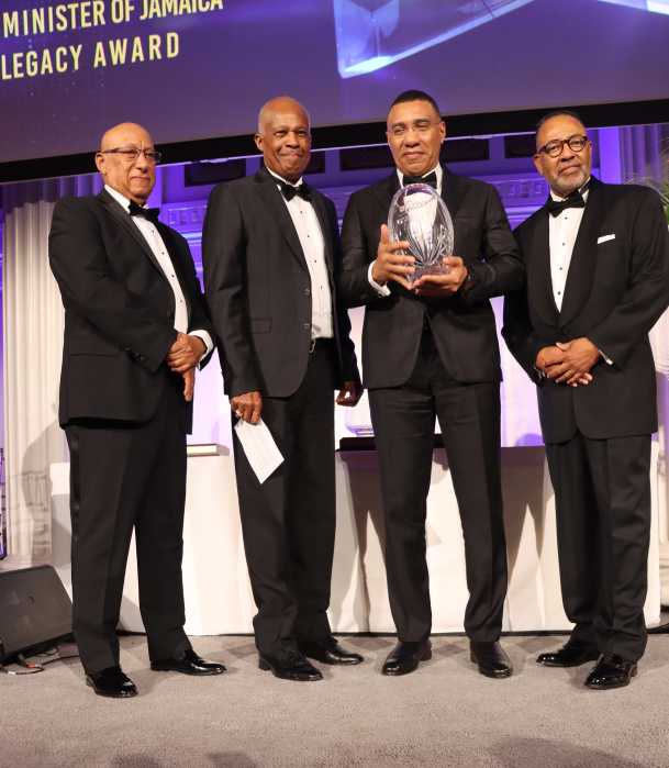 Jamaica Prime Minister Andrew Holness, second from right, receives Legacy Award, flanked by Dr. Cyrus McCalla, the Jamaican-born chairman of AFUWI, right; The University of the West Indies (UWI) Chancellor Dr. Dodridge D. Miller, left, and UWI Vice Chancellor Professor Sir Hilary Beckles, second from left.