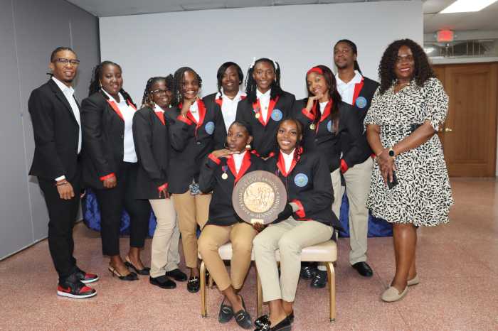Athletes from Charles E. Mills Secondary School (CEMSS) in St. Kitts and Nevis display a plaque won at Penn Relays, flanked by management: Deputy Consul General Kressell Daniel, left; and Kylla Herbert, left, coordinator of the St. Kitts and Nevis Penn Relays initiative.