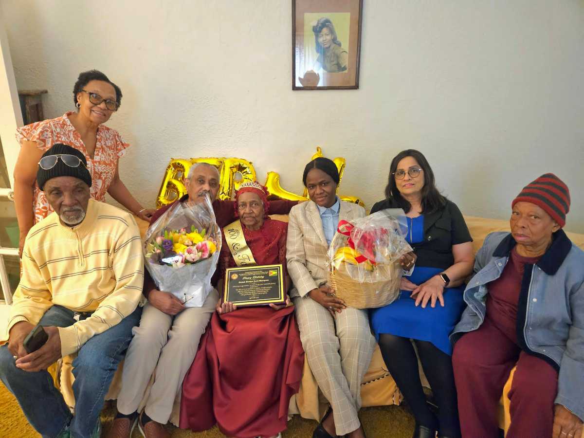 Family members from left, sitting, nephew Linden Levi, Son Jermone Serrao, Mrs. Eulah Evelyn Levi-Marque, Consulate staffers, Nacifa Watson, and Fazia Khusial, a family friend, and standing, Daughter-in-law, Judy Boyce-Serrao.