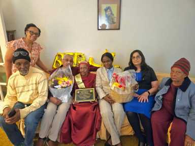 Family members from left, sitting, nephew Linden Levi, Son Jermone Serrao, Mrs. Eulah Evelyn Levi-Marque, Consulate staffers, Nacifa Watson, and Fazia Khusial, a family friend, and standing, Daughter-in-law, Judy Boyce-Serrao.