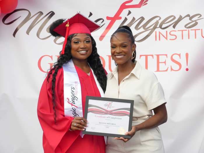 Harris presents a graduate with her certificate from Magic Fingers Institute, where aspiring beauty professionals are trained in natural hair care and styling.