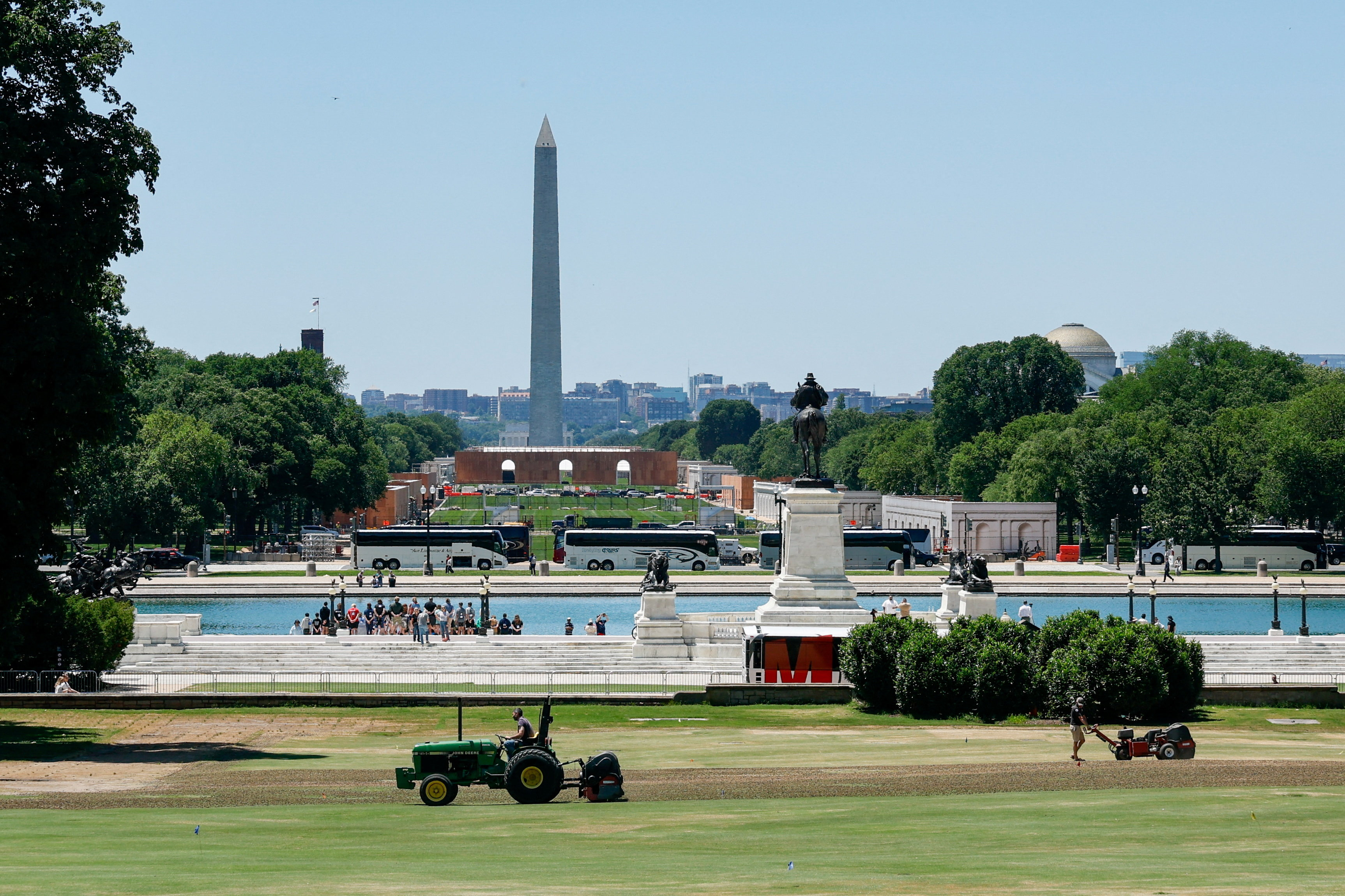 People maintain the grounds in front of the U.S. Capitol building, as construction is done on the National Mall for events related to the United States' 250th anniversary and the Washington Monument rises in the background, in Washington, D.C., U.S., June 3, 2026.