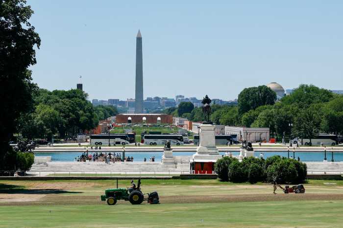 People maintain the grounds in front of the U.S. Capitol building, as construction is done on the National Mall for events related to the United States' 250th anniversary and the Washington Monument rises in the background, in Washington, D.C., U.S., June 3, 2026.