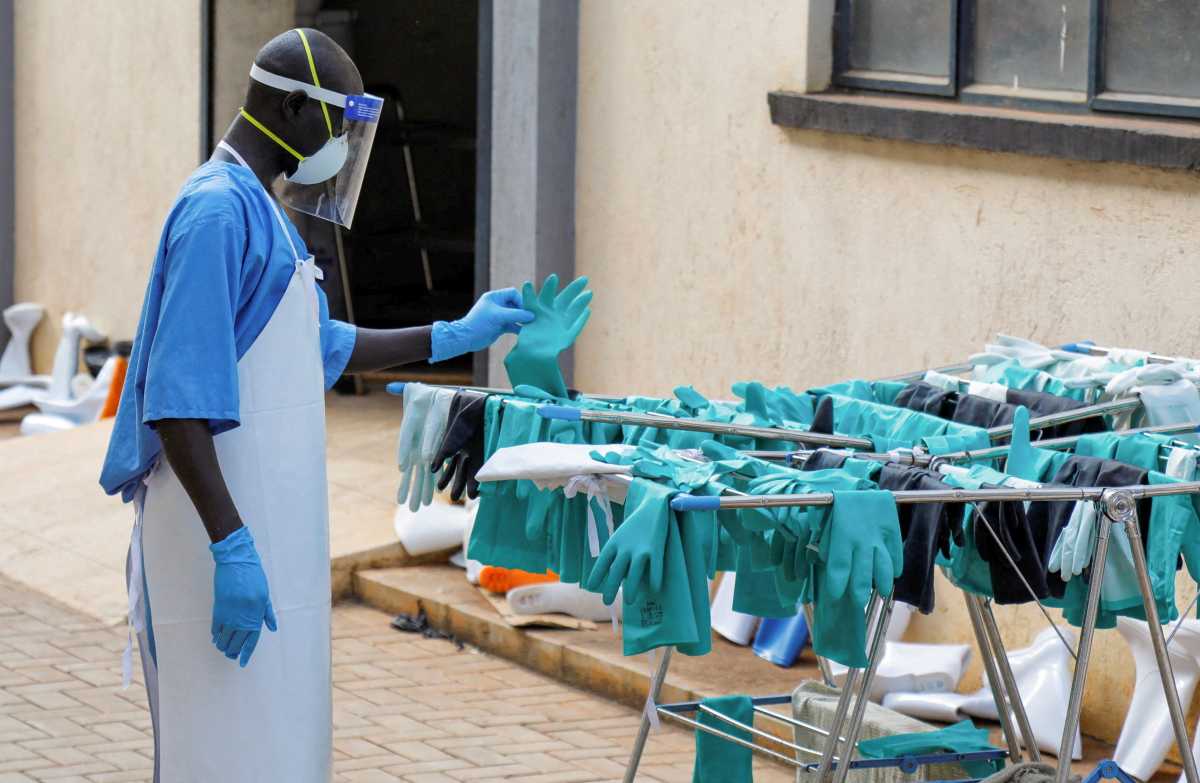 A Ugandan worker collects a rubber glove from the airing line during a visit by the Director-General of the World Health Organisation (WHO) Tedros Adhanom Ghebreyesus at the Mulago National Referral Hospital Isolation Unit, as aid agencies intensify efforts to contain a new Ebola outbreak involving the Bundibugyo Virus, in Mulago suburb, of Kampala, Uganda, June 8, 2026.