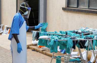 A Ugandan worker collects a rubber glove from the airing line during a visit by the Director-General of the World Health Organisation (WHO) Tedros Adhanom Ghebreyesus at the Mulago National Referral Hospital Isolation Unit, as aid agencies intensify efforts to contain a new Ebola outbreak involving the Bundibugyo Virus, in Mulago suburb, of Kampala, Uganda, June 8, 2026.
