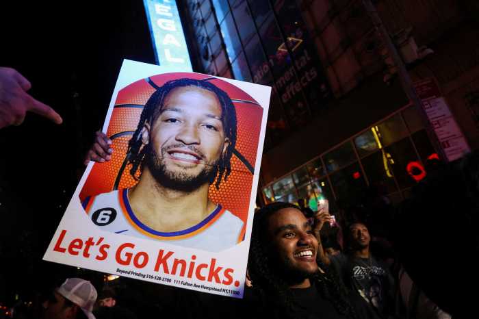A man holds a poster of New York Knicks point guard Jalen Brunson, as fans gather along 42nd Street in Times Square, on the day of Game 5 of the NBA Finals between the New York Knicks and San Antonio Spurs, in New York City, U.S., June 13, 2026.